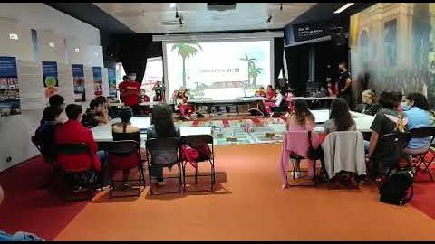 A room full of students seated at tables facing the Ciberlandia 21-22 final challenge screen, instructors at the front.